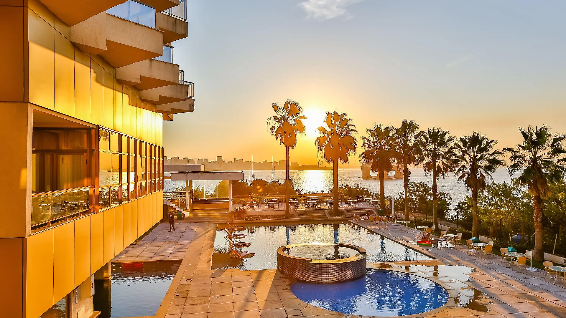 Área externa do Hotel Orizzonte Niterói com piscina e vista para a Baía de Guanabara ao pôr do sol