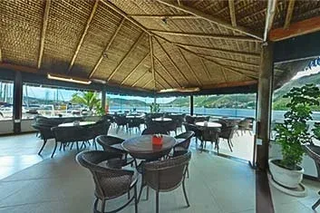 Área de convivência coberta do Clube Naval Charitas, com mesas e vista para o mar